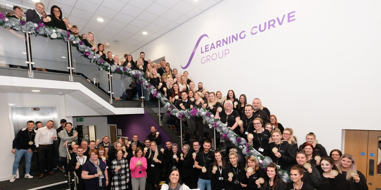 Learning Curve Group staff celebrating their IIP Gold award, with Brenda McLeish CEO.